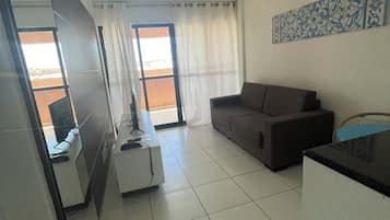 A modern living room with a sofa, a coffee table, and a dining area with a table and chairs.
