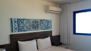 A hotel room with a bed, a nightstand, a wall-mounted air conditioner, and a window with curtains. - Atlântico Hotel (Maceió)