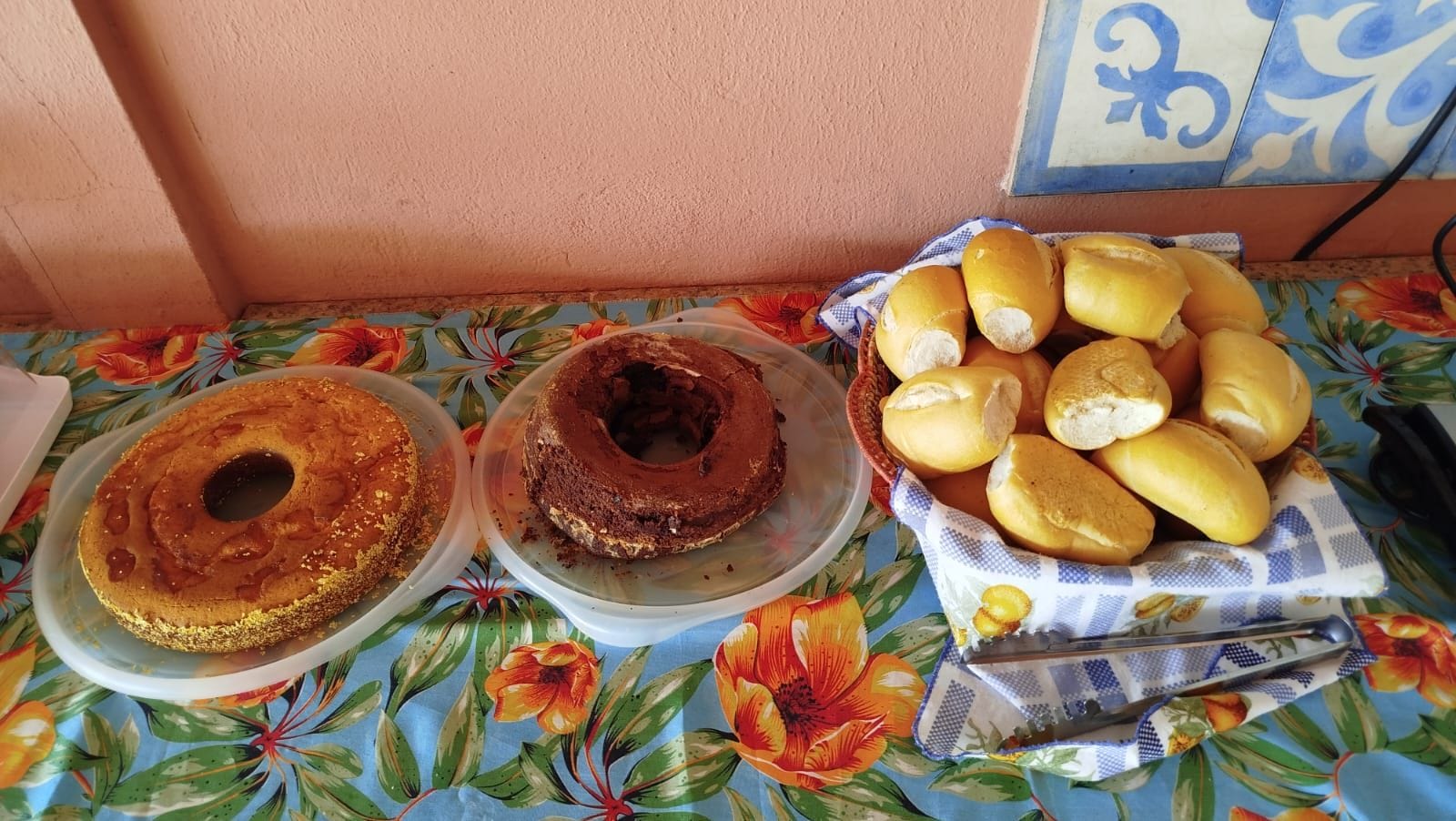A table with two cake plates and a basket of bread.