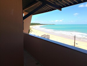 Blick auf den Strand von einem überdachten Balkon mit Meer- und Sandblick.