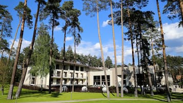 A multi-story building with a flat roof, surrounded by tall trees and a well-maintained lawn.