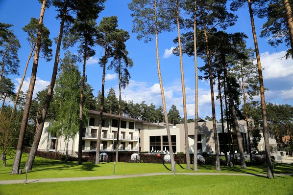 A multi-story building with a flat roof, surrounded by tall trees and a well-maintained lawn. - Grand Admiral Resort & SPA (Irpin)