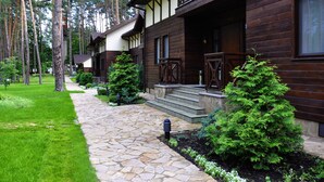 A wooden cabin with a stone pathway, surrounded by trees and greenery. - Grand Admiral Resort & SPA (Irpin)