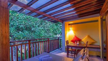 A balcony with a wooden railing, a table with chairs, a bench, and a lamp.
