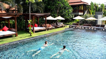 Relax by the serene pool surrounded by lush greenery and lounge under shaded umbrellas.