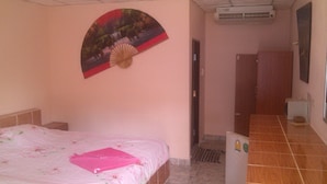 A bedroom with a bed, a fan, a door, and a tiled floor. - Klong Muang Inn (Krabi)