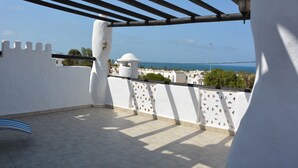 Een balkon met uitzicht op zee, witte muren en een pergola.