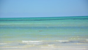 Een strand met helder turquoise water en een zandstrand.