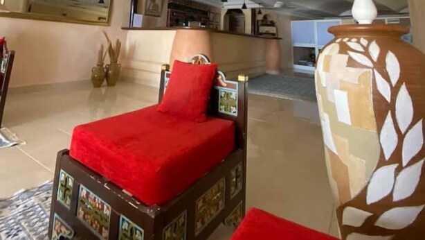 Een kamer met een rode bed, een grote vaas en een plafond met decoratieve patronen.