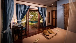 Una habitación con una cama, una mesa con una silla, una hamaca y vistas al exterior.