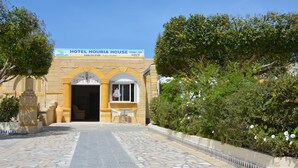 A hotel entrance with a reception desk, a signboard, and a paved pathway leading to the entrance. - Houria House Sable d'Or (Mahdia)