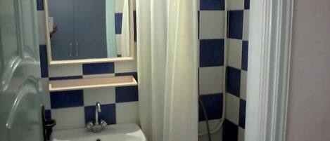 Un baño con un lavamanos blanco, un espejo encima y baldosas azules y blancas a cuadros en las paredes.