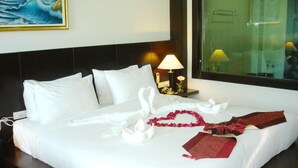 Habitación de hotel con una cama bien tendida, un cuadro en la pared y una ventana con vistas.