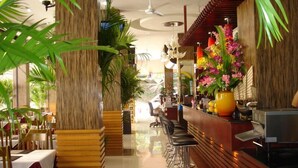 Un restaurante con interior de madera, zona de bar y plantas tropicales.