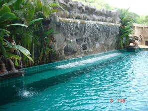 Una piscina al aire libre, sombrillas, sillones reclinables de piscina