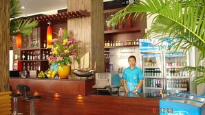 Vestíbulo de hotel con mostrador de recepción, un gran arreglo floral y una exhibición de helados Nestlé.
