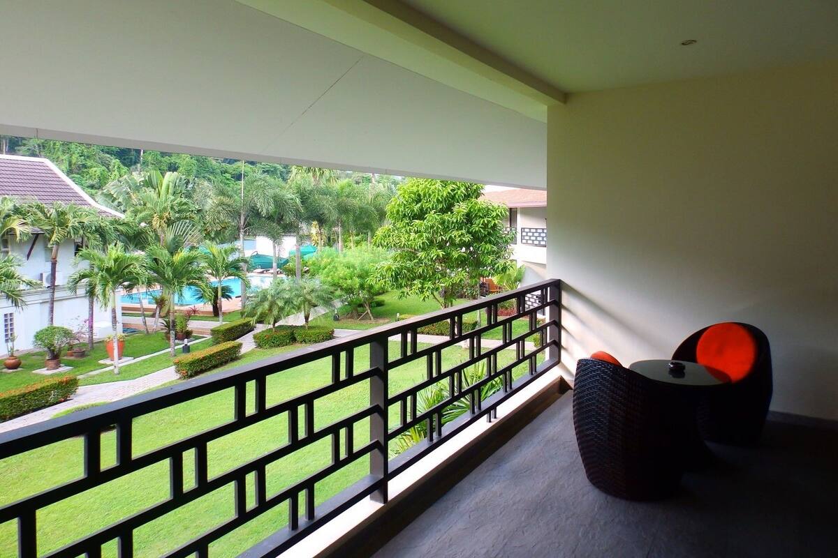 A balcony with a view of a pool and lush greenery.