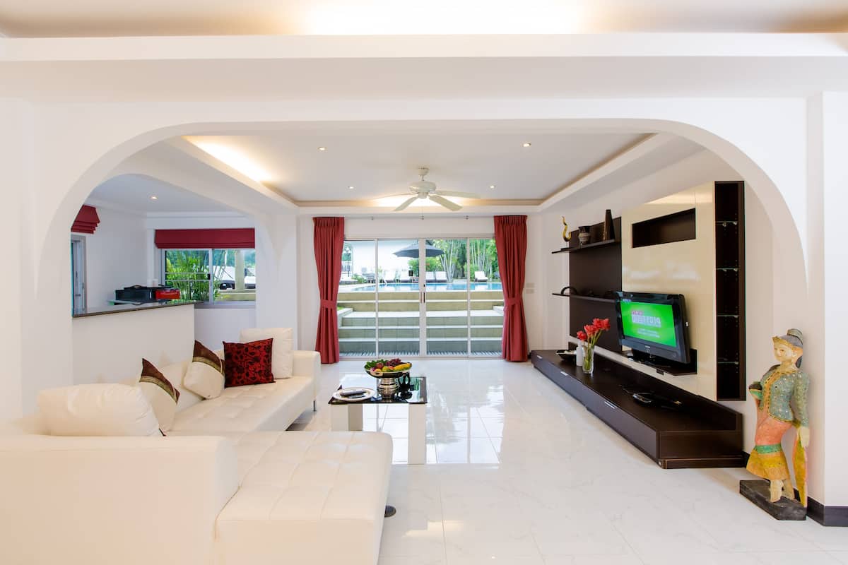 A modern living room with a white sofa, a coffee table, a flat-screen TV, and a statue.