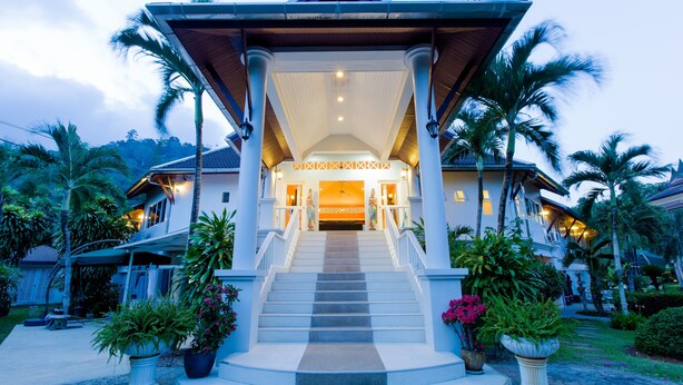 A grand hotel entrance with a central staircase, palm trees, and a well-lit facade. - Serenity Lakeside Resort (Kathu)