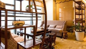 Un espacio de sala acogedor con un sofá, estanterías de madera y un ventanal grande.