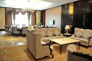 A hotel lobby with a sofa set, a coffee table, and a dining area with chairs and a table. - Wansheng International Hotel (Chongqing)