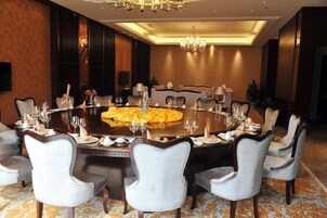 Una mesa redonda de comedor con varias sillas, una araña y piso alfombrado.
