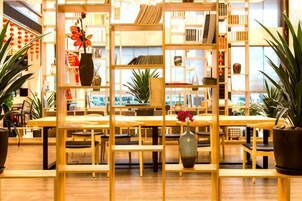 Una librería con estanterías y mesas de madera, plantas en macetas y una gran variedad de libros.