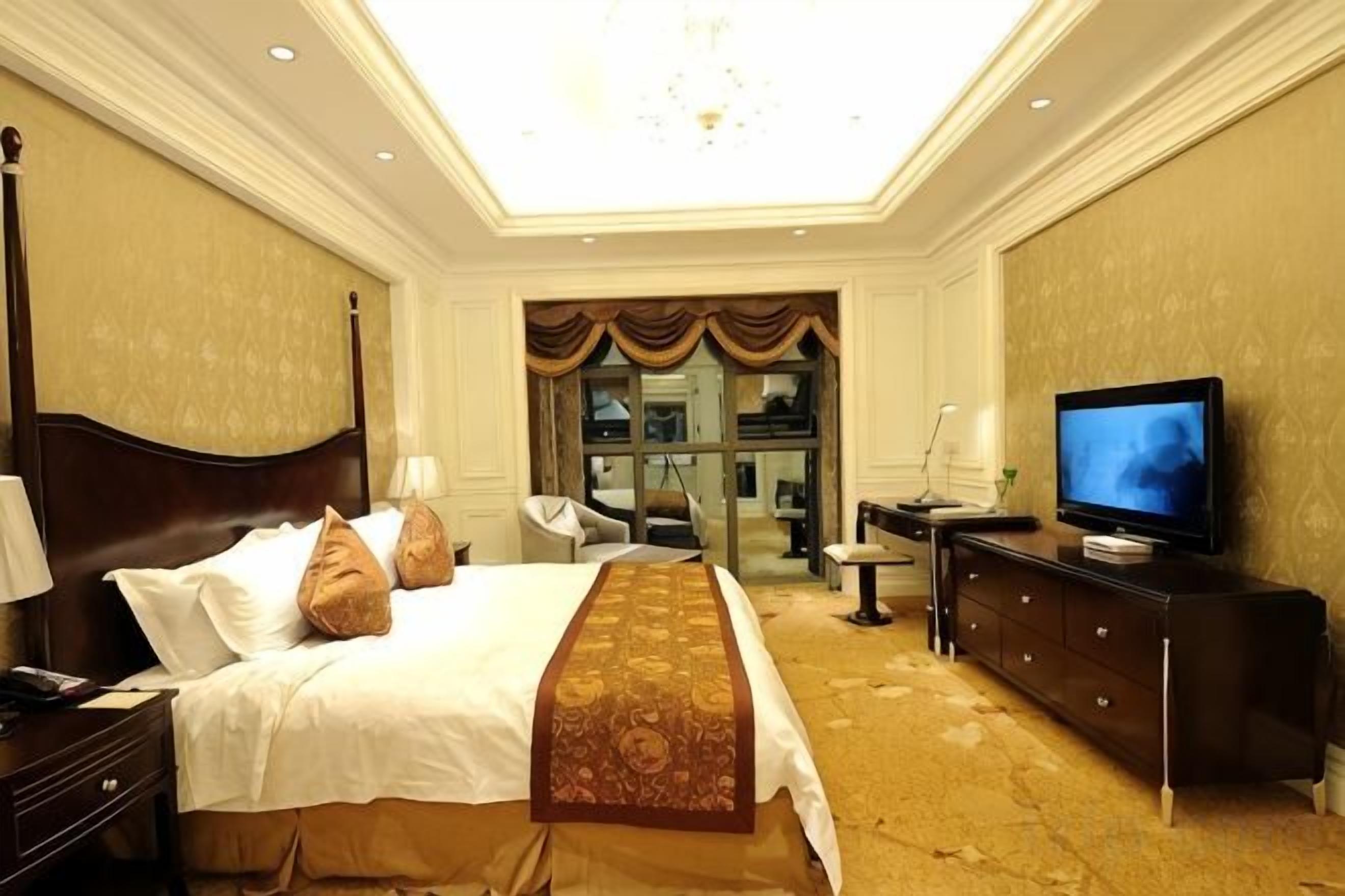 Una habitación de hotel con una cama grande, televisión, escritorio y silla.
