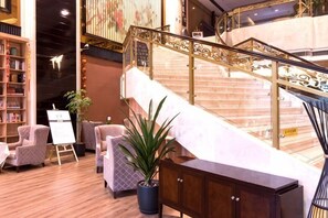 Un vestíbulo con una escalera, una zona de estar y un mostrador de recepción.
