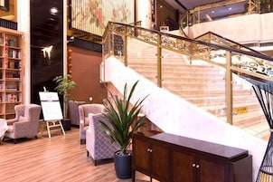 Un vestíbulo con una escalera, una zona de estar y un mostrador de recepción.