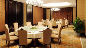 Une salle de conférence équipée d’une table ronde, de chaises et d’un lustre.