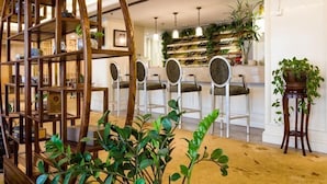 Un vestíbulo de hotel con una estantería de madera, un escaparate de zapatos y una zona de bar con taburetes.
