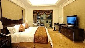 Una habitación de hotel con una cama grande, televisión, escritorio y una silla.