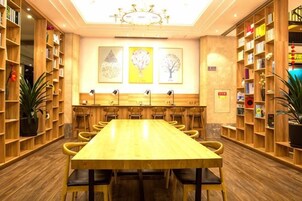 Un salón de conferencias con una larga mesa, varias sillas y estanterías a ambos lados.