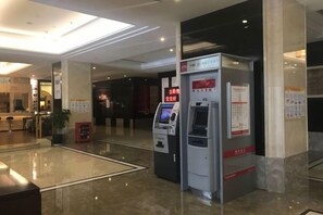 Un vestíbulo moderno con mostrador de recepción, quiosco de autoservicio y panel informativo digital.