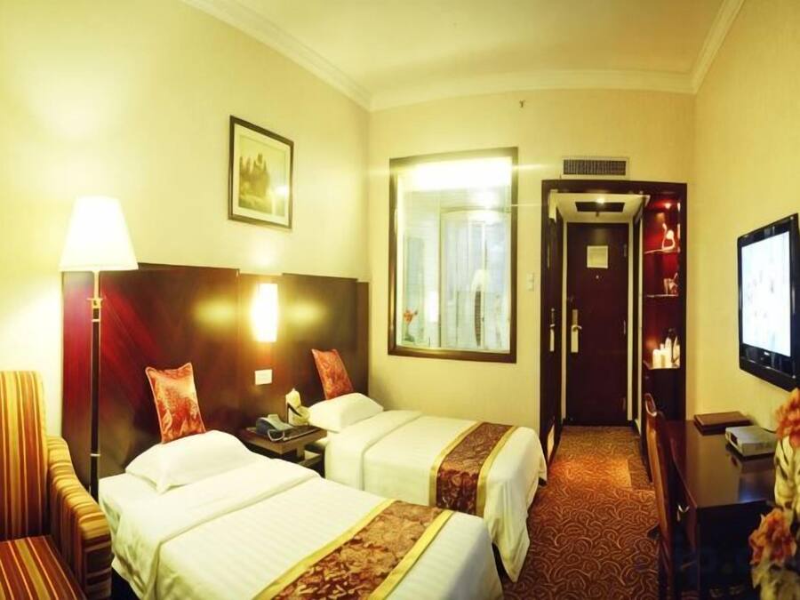 A hotel room with two beds, a TV, a desk, and a mirror.