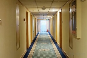 A hotel hallway with a carpeted floor, doors on both sides, and a light source at the end. - Yan'an Grand Hotel (Liuzhou)