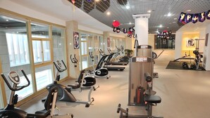 Un gimnasio con máquinas de cardio, estaciones de pesas y espejos.
