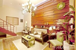 A modern living room with a sofa, coffee table, and chairs, a staircase, and a decorative wall panel. - Minglan Holiday Hotel (Weihai)