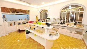 Una habitación bien iluminada con una mesa buffet central, paredes blancas y un suelo amarillo con estampado.