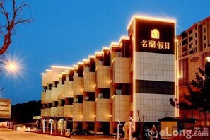 A modern hotel with a unique geometric facade and illuminated signage. - Minglan Holiday Hotel (Weihai)