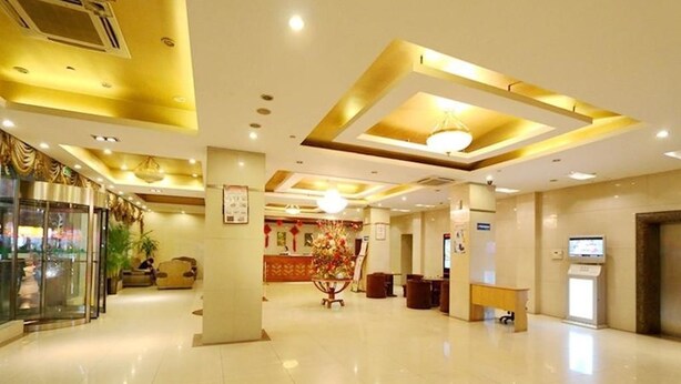 Um hall amplo com piso lustroso, um balcão de recepção e uma área de estar com uma cadeira decorativa.