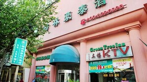 Fachada de hotel com sinalização para 'Green Treasure TV' e área de entretenimento 'KTV'.
