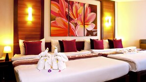 Una habitación de hotel con dos camas, ropa de cama roja y blanca, una obra de arte floral grande en la pared y una mesita de noche con una lámpara.
