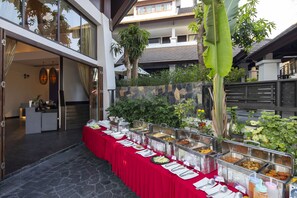 A buffet setup with multiple food stations, a red tablecloth, and a stone wall backdrop. - Samed Pavilion Resort & Restaurant (Rayong)