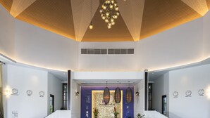 Un vestíbulo de hotel moderno con una recepción, un candelabro y relojes que marcan diferentes ciudades.