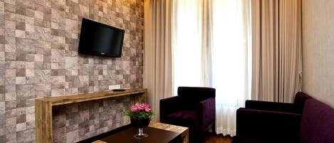 Una sala de estar moderna con una pared de diseño de piedra, un televisor montado, un banco de madera, un sillón morado y un sofá.
