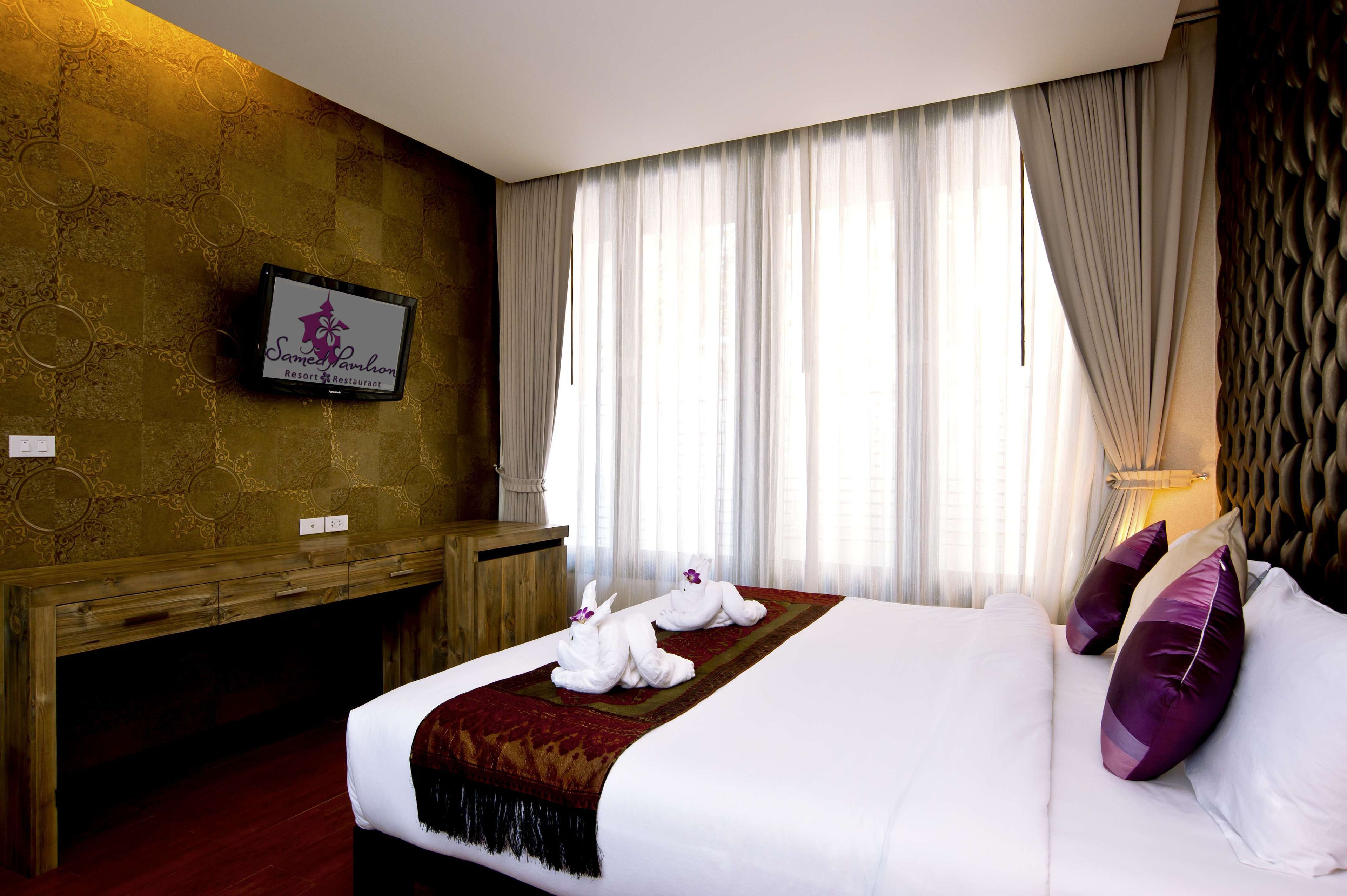 A hotel room with a large bed, a wooden desk, and a television mounted on the wall.