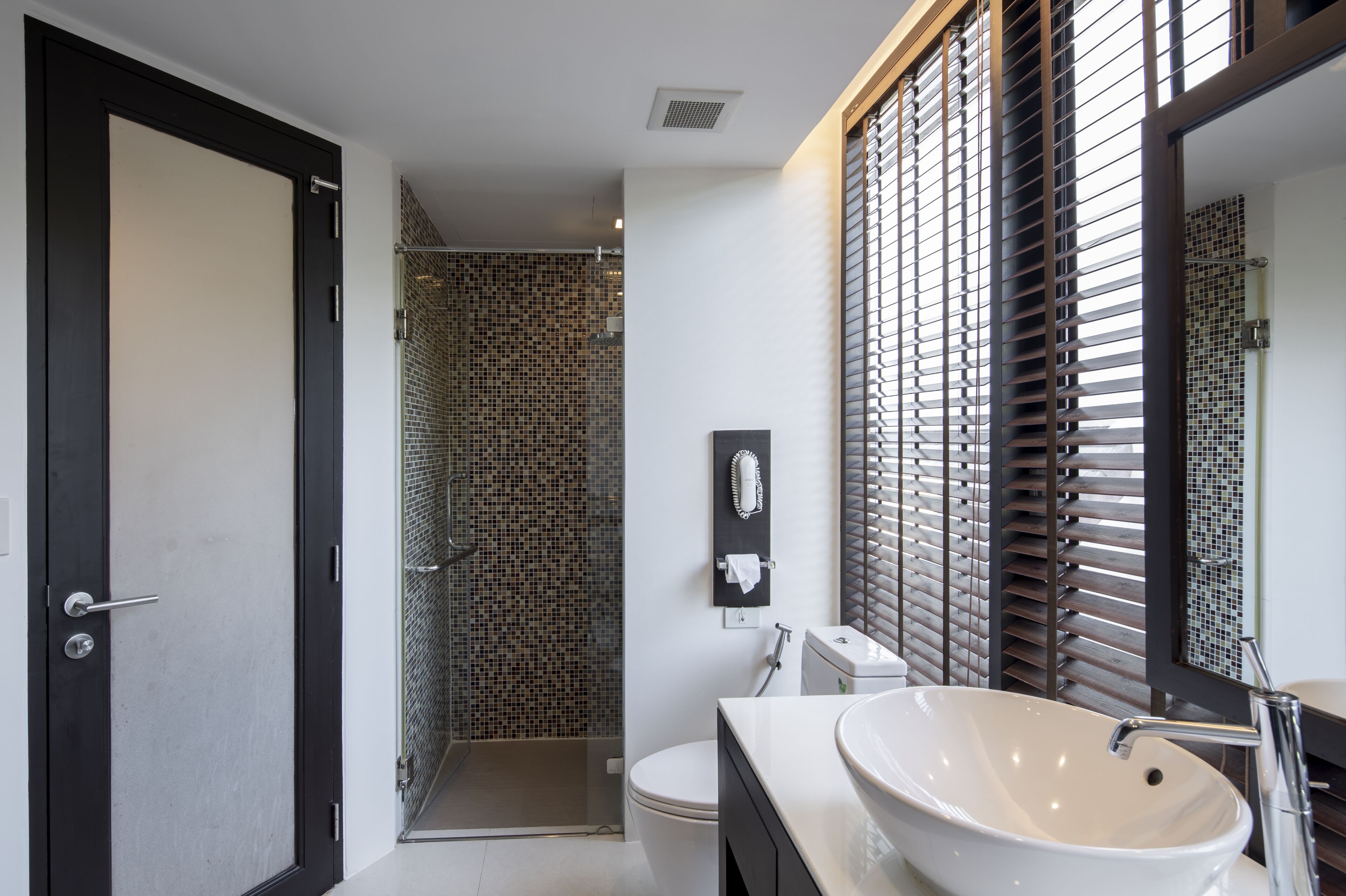Un baño moderno con un lavabo blanco grande, un inodoro y una zona de ducha con pared de azulejos.