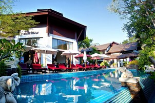 Una piscina al aire libre, sombrillas, sillones reclinables de piscina